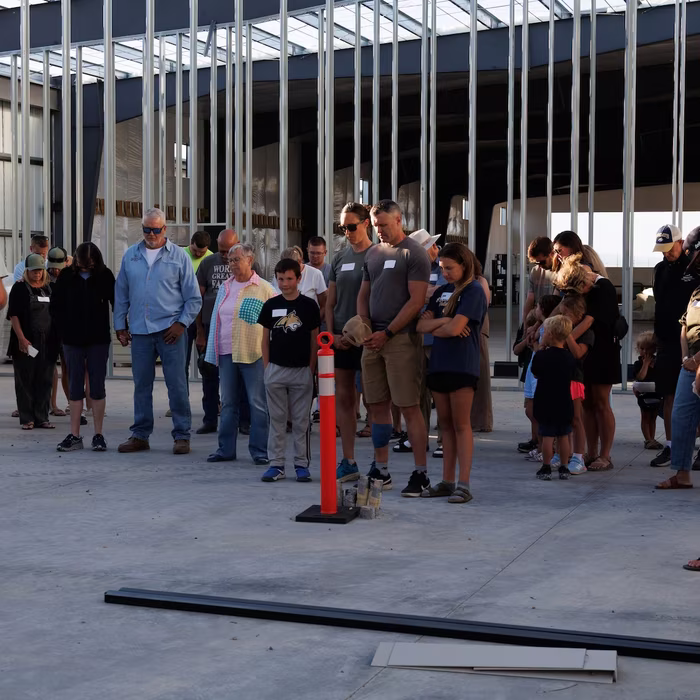 Congregation with heads bowed in prayer inside the steel frame